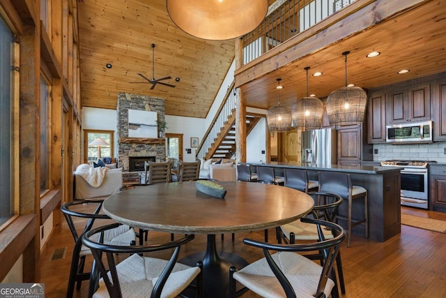 dining room with dark wood-style floors, stairway, a high ceiling, a fireplace, and recessed lighting