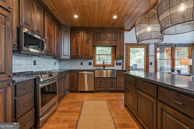 kitchen featuring light wood finished floors, decorative backsplash, wood ceiling, stainless steel appliances, and a sink