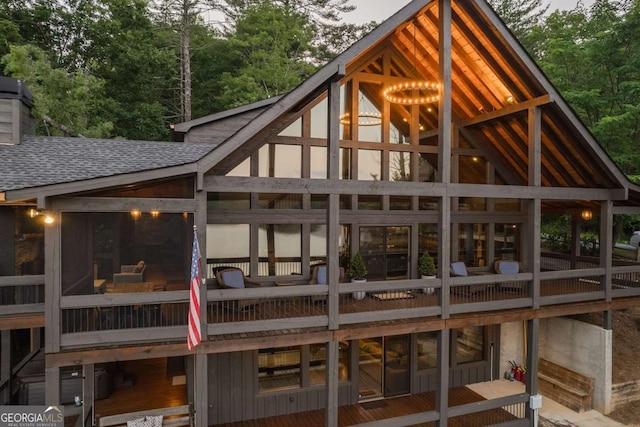 back of house with roof with shingles and a sunroom