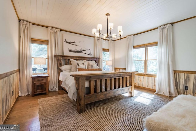 bedroom featuring a wainscoted wall, multiple windows, wooden ceiling, and wooden walls