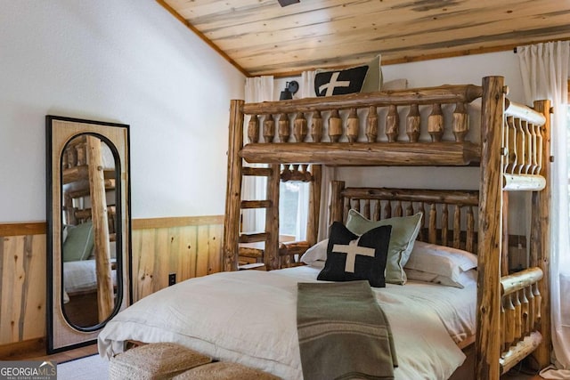 bedroom featuring wooden ceiling, wainscoting, vaulted ceiling, and wooden walls