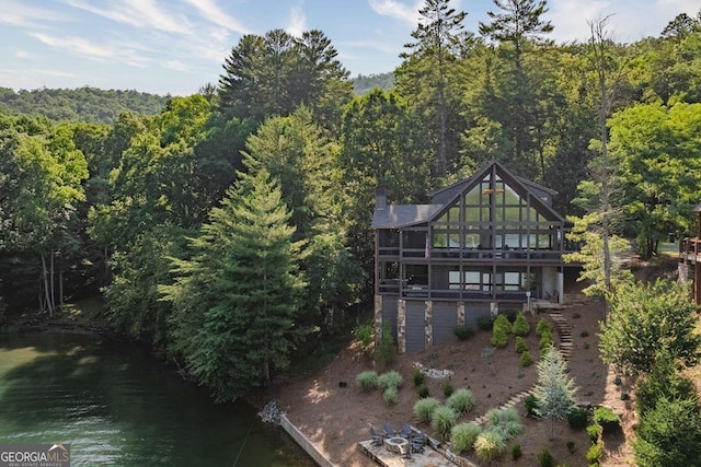 rear view of property with a water view, a wooded view, and stairs