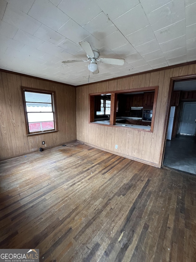 unfurnished living room featuring wood walls, hardwood / wood-style floors, and ceiling fan