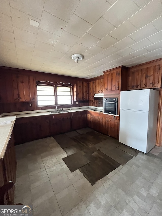 kitchen featuring tile patterned floors, stainless steel oven, light countertops, and freestanding refrigerator