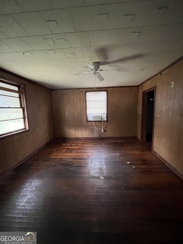 unfurnished room with wooden walls, dark wood-style flooring, and a healthy amount of sunlight