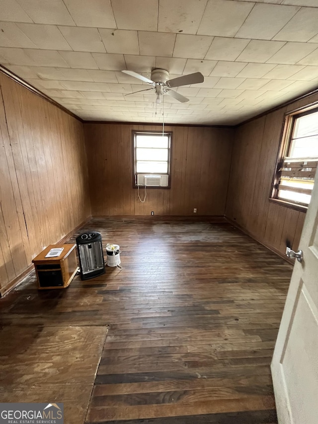 spare room featuring dark wood-style floors, ceiling fan, wooden walls, and a wealth of natural light