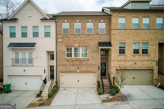 townhome / multi-family property featuring a garage, a standing seam roof, concrete driveway, and brick siding