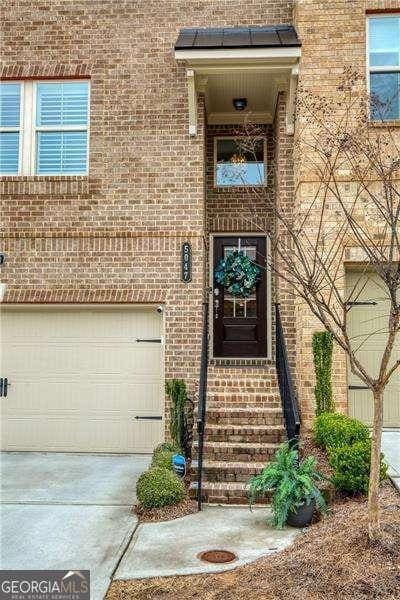 view of exterior entry featuring a garage, concrete driveway, and brick siding