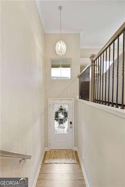 doorway featuring a chandelier, a towering ceiling, baseboards, and wood finished floors