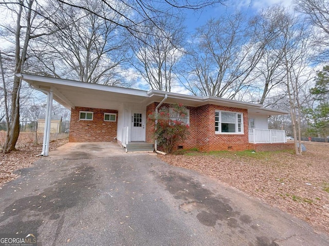 ranch-style house featuring a carport, driveway, brick siding, and crawl space