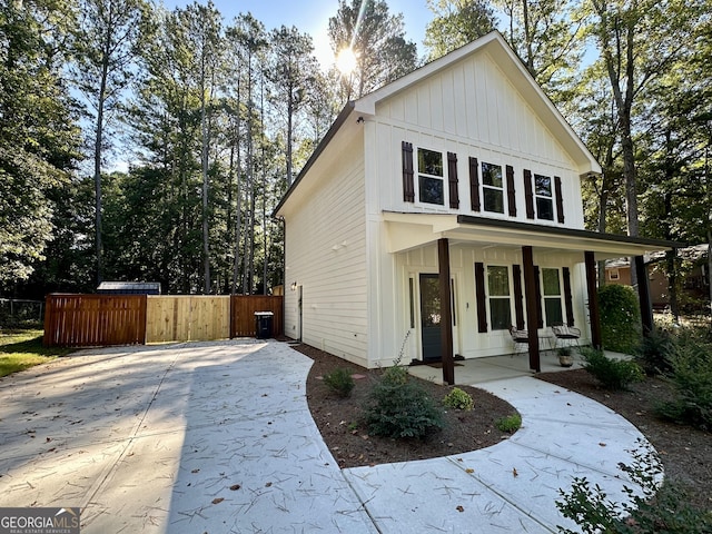 view of front facade with board and batten siding, covered porch, and fence