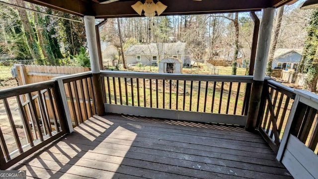 wooden terrace featuring an outbuilding, fence, and a storage shed