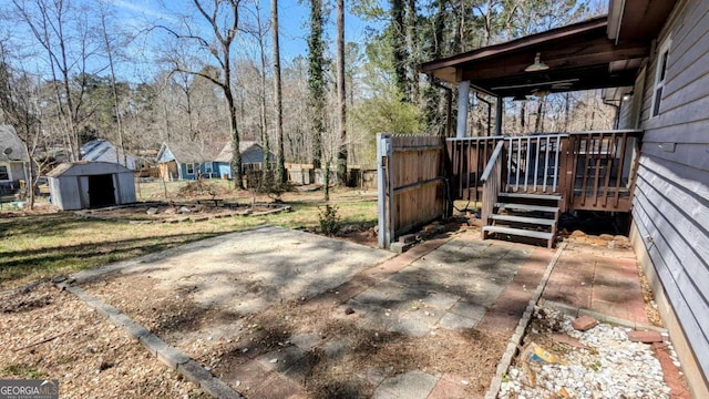 view of yard with an outbuilding, fence, a wooden deck, a shed, and a patio area