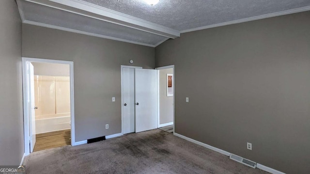 unfurnished bedroom featuring a textured ceiling, lofted ceiling with beams, carpet floors, visible vents, and baseboards