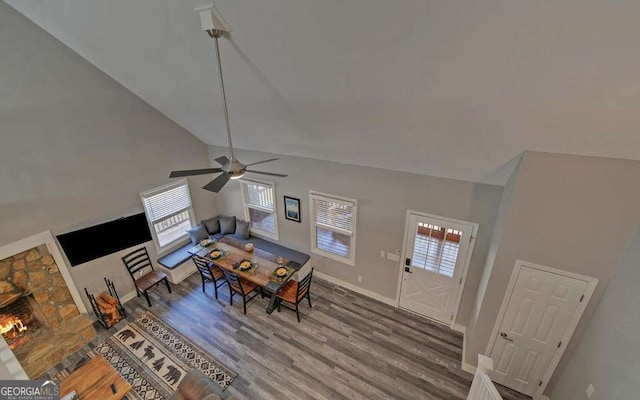 dining area with baseboards, high vaulted ceiling, a healthy amount of sunlight, and wood finished floors