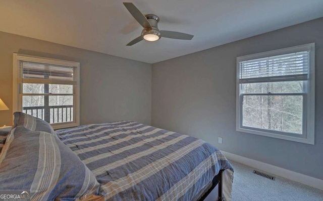 carpeted bedroom with visible vents, multiple windows, a ceiling fan, and baseboards