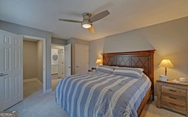 bedroom with ceiling fan, connected bathroom, baseboards, and light carpet