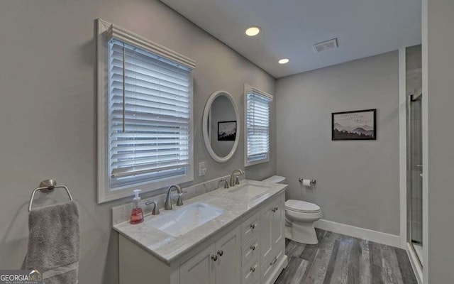 bathroom with an enclosed shower, wood finished floors, visible vents, and a sink