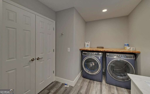 washroom with laundry area, wood finished floors, washing machine and dryer, and baseboards