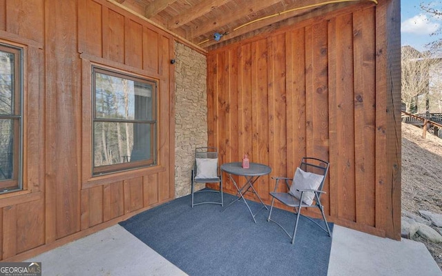 exterior space with beamed ceiling, wooden walls, and wood ceiling