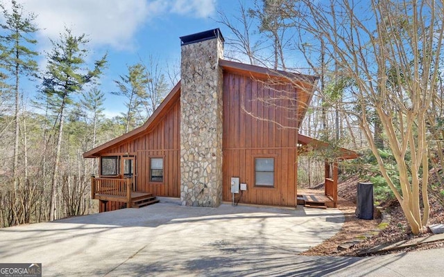 exterior space featuring a wooden deck, board and batten siding, and a chimney