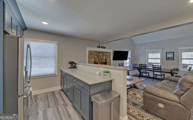 kitchen featuring lofted ceiling, a peninsula, open floor plan, and freestanding refrigerator