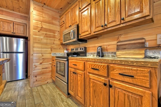 kitchen with wooden walls, appliances with stainless steel finishes, and brown cabinetry