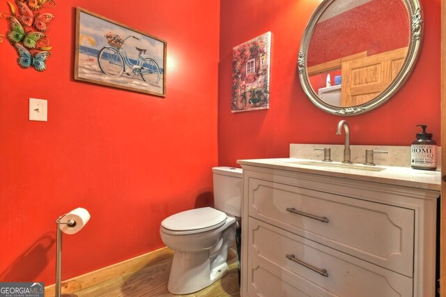 bathroom with wood finished floors, vanity, toilet, and baseboards