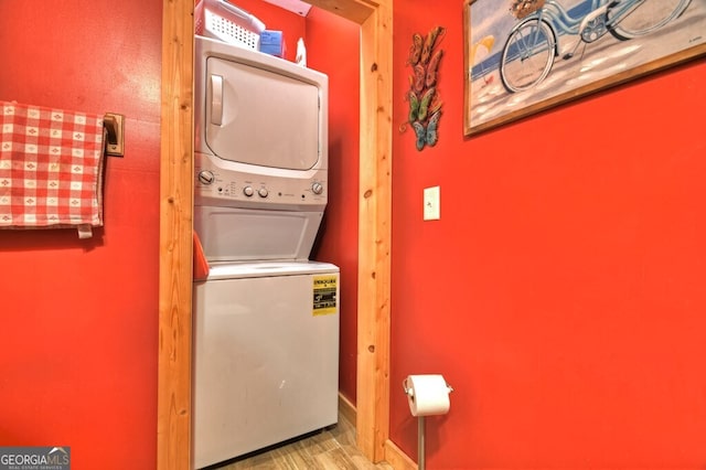 washroom featuring stacked washer and dryer, laundry area, and wood finished floors