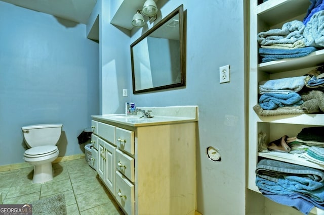half bathroom featuring baseboards, vanity, toilet, and tile patterned floors