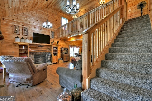 living area featuring stairway, a notable chandelier, wooden walls, and hardwood / wood-style floors