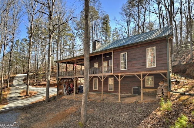 exterior space featuring a chimney, central AC unit, and metal roof