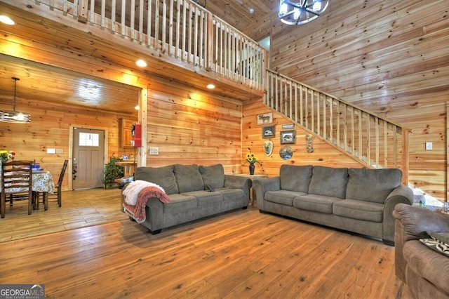living area with wooden walls, wood ceiling, stairs, and wood-type flooring