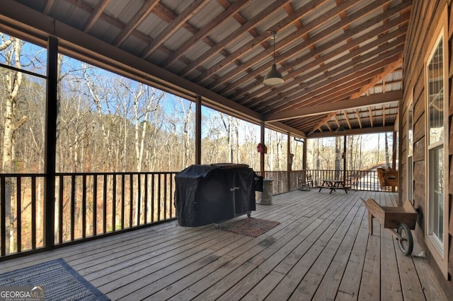 wooden terrace with area for grilling and a wooded view