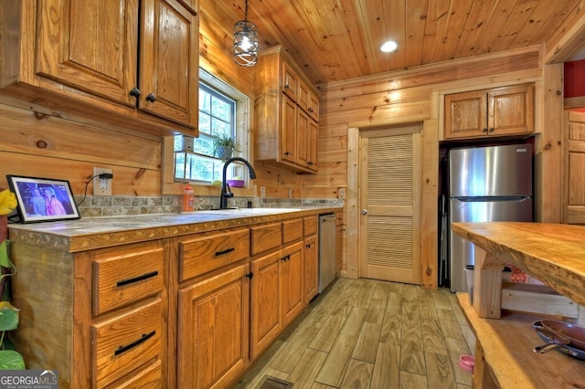 kitchen with light wood-style flooring, wood walls, wood ceiling, appliances with stainless steel finishes, and brown cabinets