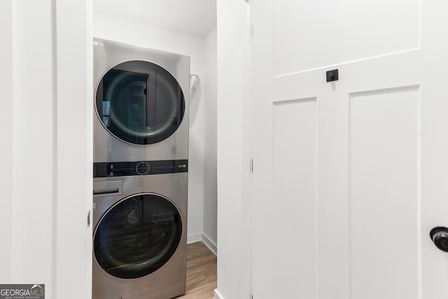 laundry room with wood finished floors, stacked washer and clothes dryer, and laundry area