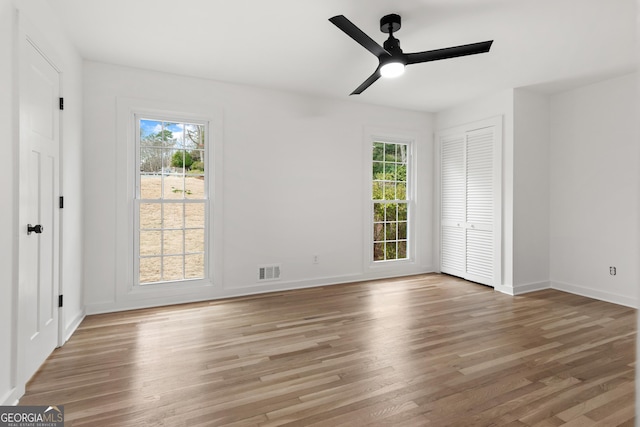 unfurnished bedroom with light wood-type flooring, multiple windows, and baseboards