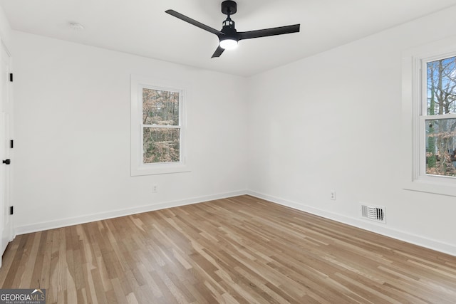 unfurnished room with ceiling fan, light wood-style flooring, visible vents, and baseboards