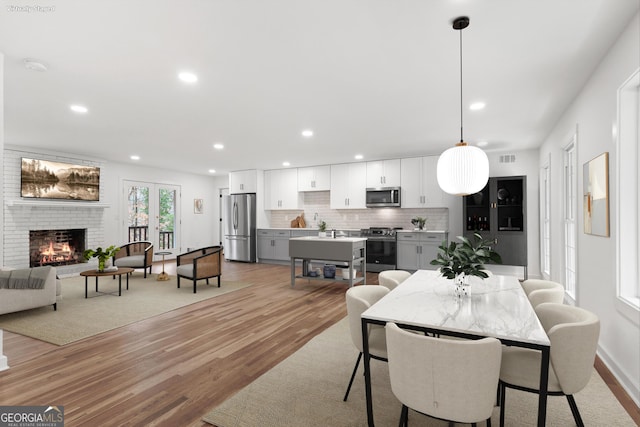 dining space with a brick fireplace, recessed lighting, visible vents, and light wood-style floors