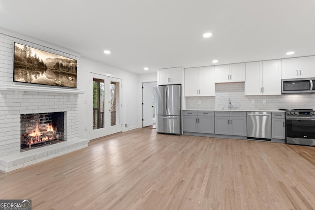 kitchen with light wood-style floors, tasteful backsplash, appliances with stainless steel finishes, and a sink