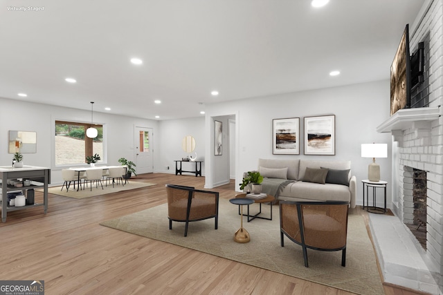 living room featuring light wood-style flooring, a fireplace, baseboards, and recessed lighting