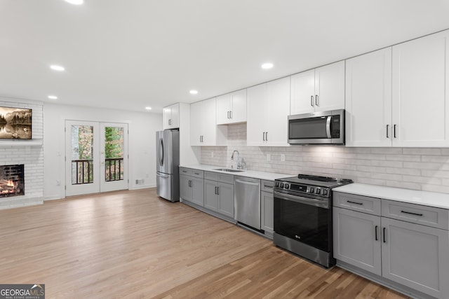 kitchen featuring light wood-style floors, appliances with stainless steel finishes, gray cabinets, and a sink