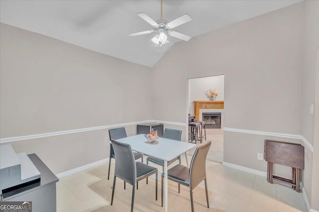 dining area with ceiling fan, baseboards, vaulted ceiling, and a tile fireplace