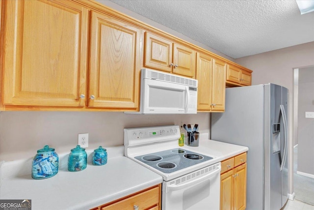 kitchen with a textured ceiling, light countertops, white appliances, and light brown cabinets