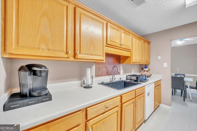 kitchen with a textured ceiling, white dishwasher, a sink, visible vents, and light countertops