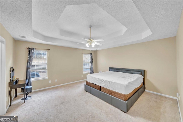 carpeted bedroom with a tray ceiling, multiple windows, and visible vents