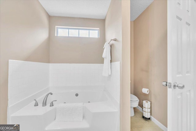 full bathroom with baseboards, toilet, a tub with jets, tile patterned floors, and a textured ceiling