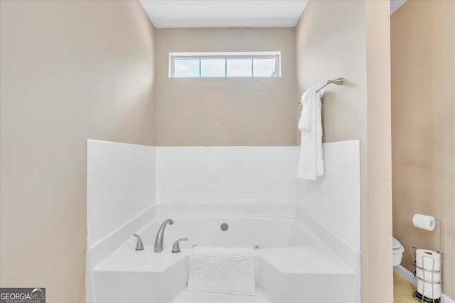 bathroom with a textured ceiling, toilet, and a bath