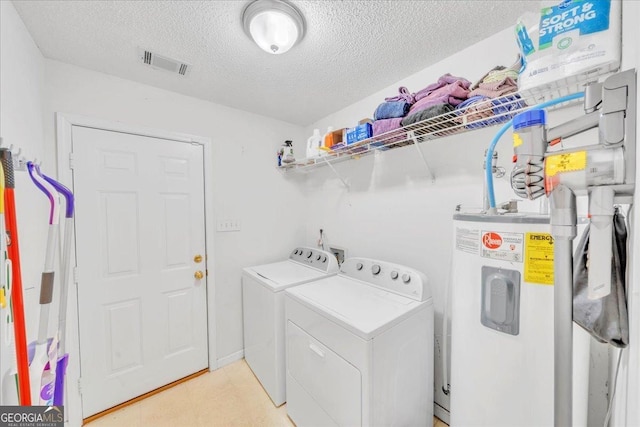 laundry room with a textured ceiling, laundry area, visible vents, water heater, and washer and clothes dryer