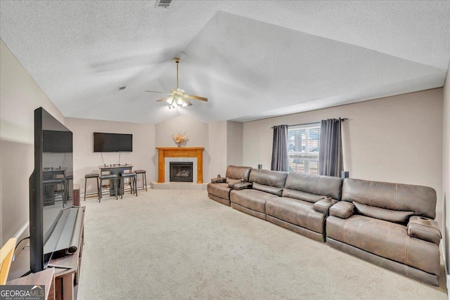 carpeted living area with a ceiling fan, lofted ceiling, a fireplace, and a textured ceiling